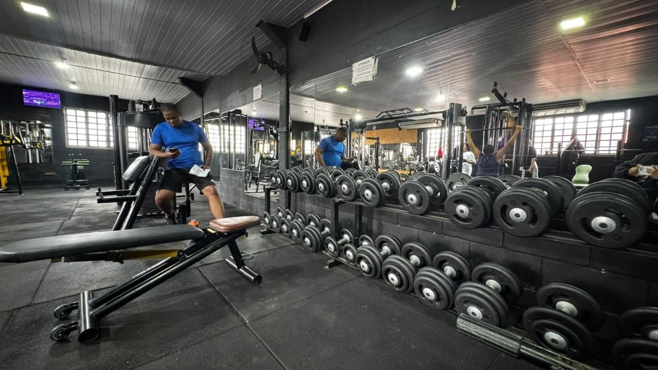 Halteres e bancos no espaço de musculação da Cross Arena